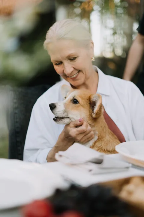 A smiling older woman holding her dog